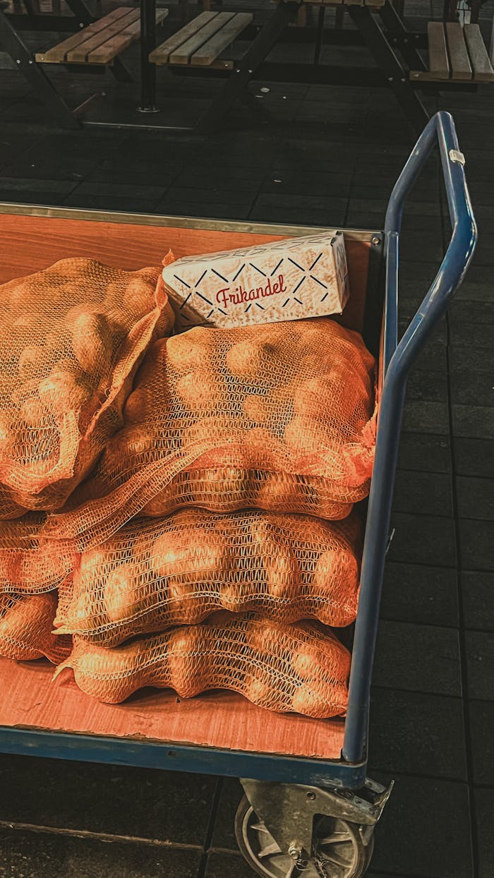 services-06 A cart carrying sacks of potatoes and a frikandel box at a market.